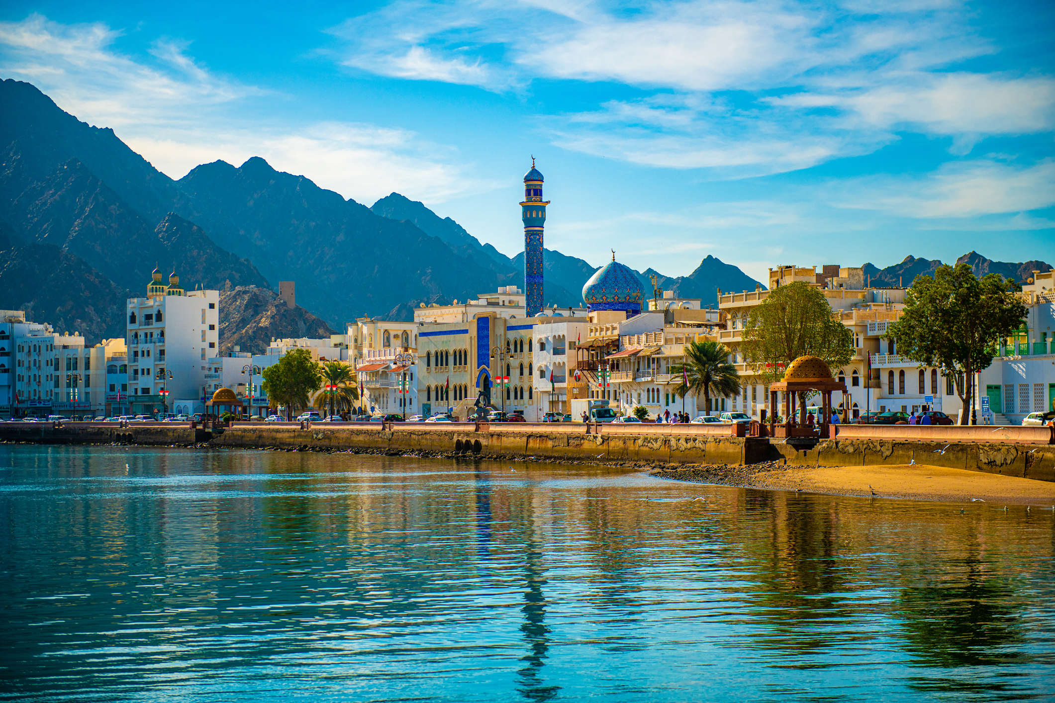 Landscape view of the ancient buildings stretches along the harbor overlooks mountainous rocky formations, Muscat, Oman - December 02, 2018